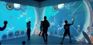 Group of children playing with balls on an interactive wall representing an underwater world.