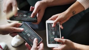 Des amis jouant sur trois téléphones en cercle, sur un jeu en coopération