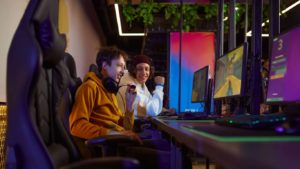 Deux jeunes avec casques de gaming jouant à des jeux vidéo devant des PC