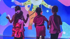 Quatre petites filles dansant devant un mur interactif, au rythme des clips musicaux dans le mode disco de NeoXperiences