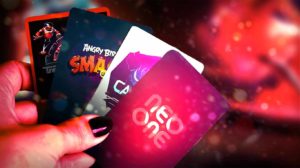 Main tenant quatre cartes avec logos Neo-One et logos de jeux pour l'option cashless