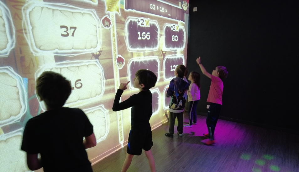 Enfants jouant en équipe à un jeu de mathématiques (abakus) sur un mur interactif Neo One