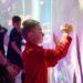 Children playing with balls on a colourful and luminous interactive wall in an immersive room.