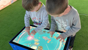 Deux enfants jouent à un jeu de pêche sur la table digitale interactive Neo GameBoard S de NeoXperiences