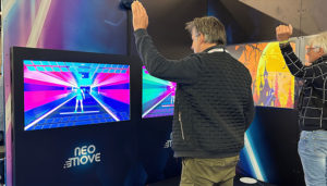 Deux personnes interagissent avec des écrans Neo Move en levant les bras, dans un jeu de captation de mouvement