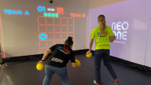Deux personnes jouant au morpion projeté sur un mur interactif dans une salle immersive NeoXperiences