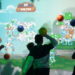 Des enfants jouent à Angry Birds Smash sur un mur interactif géant, en lançant des balles sur les structures et des cochons verts à détruire
