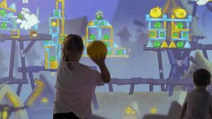 Enfant lançant une balle sur le mur interactif Neo-One avec le jeu Angry Birds